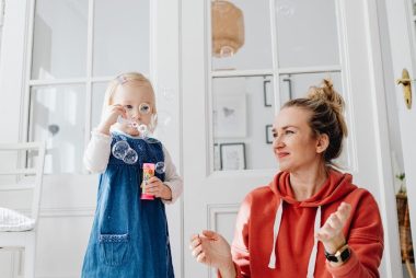 A joyful moment of a mother and daughter playing with bubbles indoors.